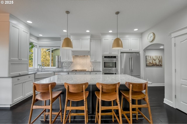 kitchen featuring pendant lighting, a center island, sink, white cabinetry, and stainless steel appliances