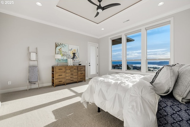 bedroom with a tray ceiling, crown molding, visible vents, and light carpet