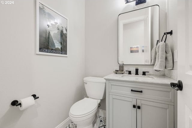 half bathroom featuring toilet, vanity, and baseboards