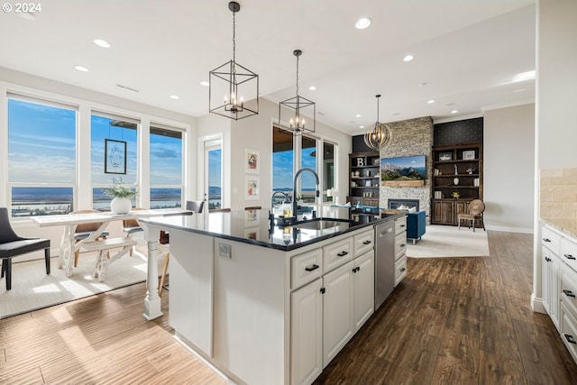 kitchen featuring open floor plan, dark wood-type flooring, a stone fireplace, white cabinetry, and a sink