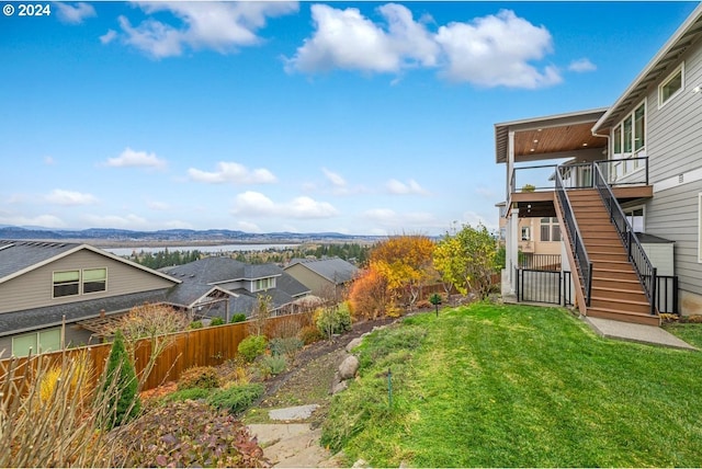 view of yard with a deck with mountain view, stairway, and fence