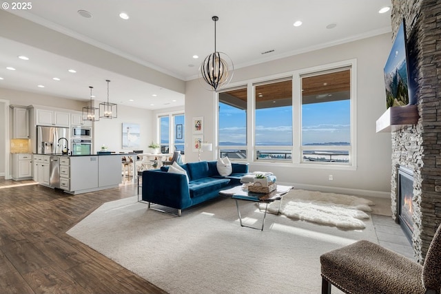 living area featuring a chandelier, a fireplace, and ornamental molding