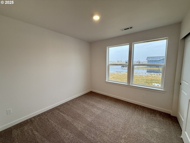 carpeted empty room featuring visible vents and baseboards