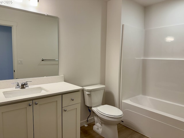 bathroom featuring toilet, washtub / shower combination, wood finished floors, and vanity