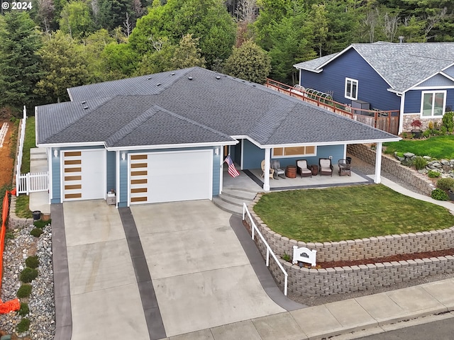 view of front of property featuring a front lawn, fence, concrete driveway, roof with shingles, and an attached garage