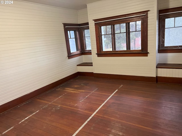 spare room with wooden walls, radiator heating unit, and dark hardwood / wood-style floors