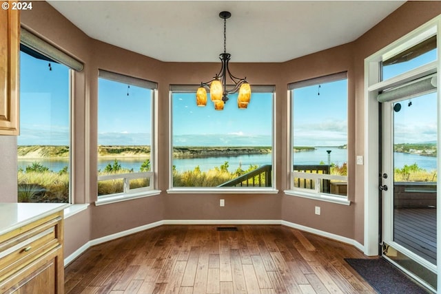 unfurnished sunroom featuring plenty of natural light, a water view, and a chandelier