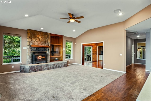 unfurnished living room featuring plenty of natural light, a stone fireplace, lofted ceiling, and dark wood-type flooring