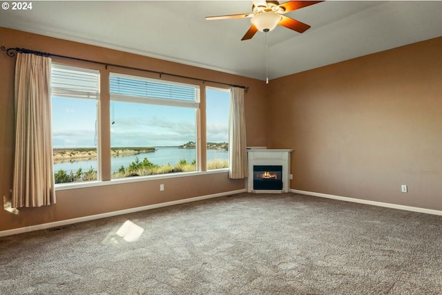 unfurnished living room featuring carpet flooring, plenty of natural light, and a water view