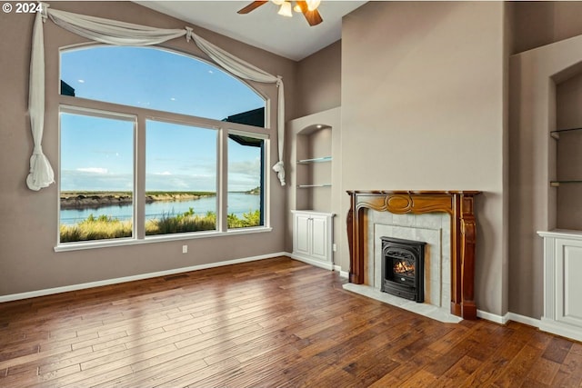 unfurnished living room with dark hardwood / wood-style flooring, ceiling fan, and a water view