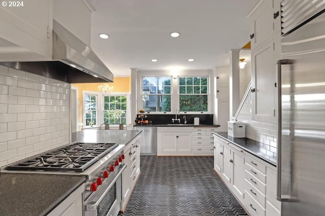 kitchen with sink, white cabinetry, backsplash, stainless steel appliances, and island range hood