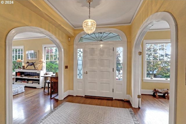 entryway featuring dark hardwood / wood-style flooring, crown molding, and a chandelier