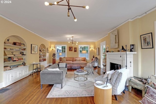 living room featuring hardwood / wood-style flooring, ornamental molding, a chandelier, and built in shelves