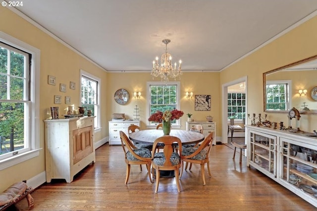 dining area with a notable chandelier, a wealth of natural light, wood-type flooring, and ornamental molding