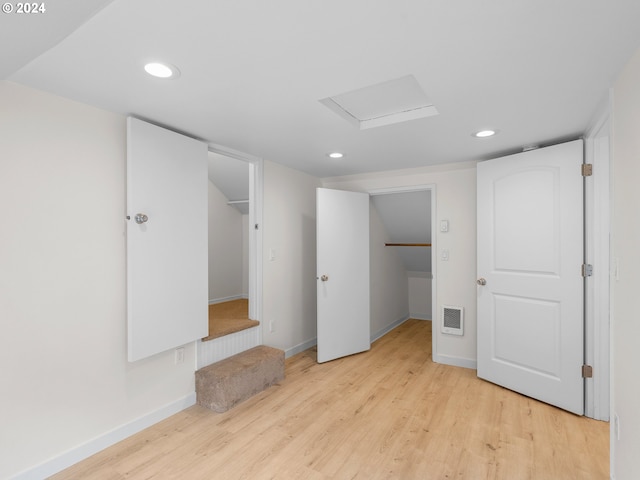 unfurnished bedroom with a spacious closet, a closet, and light wood-type flooring