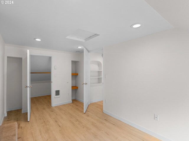 unfurnished bedroom featuring a walk in closet, light hardwood / wood-style flooring, and a closet