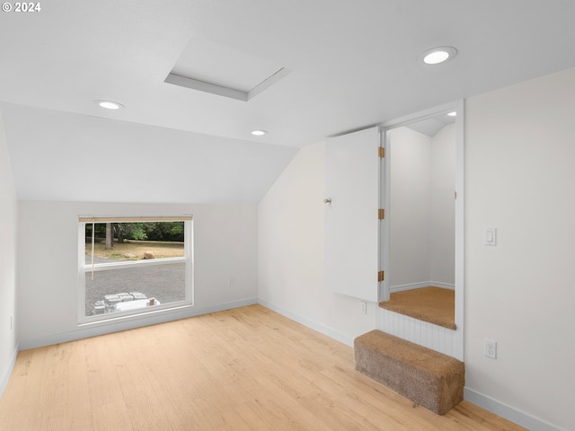 additional living space with light wood-type flooring and lofted ceiling