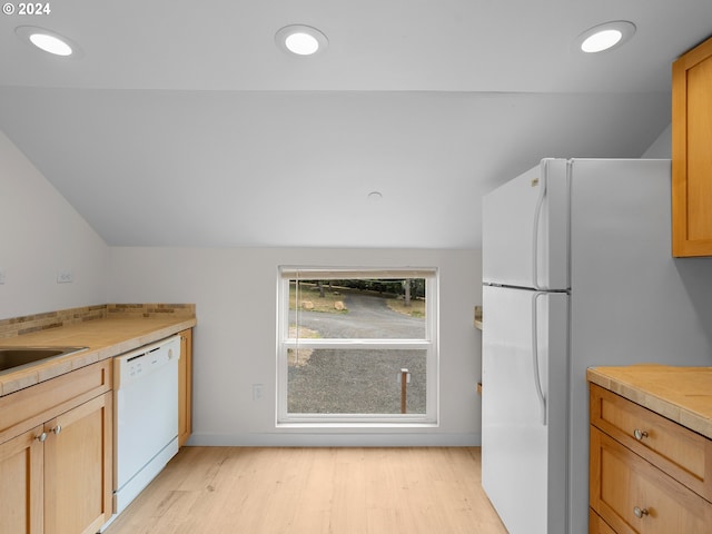 kitchen featuring white appliances, light hardwood / wood-style flooring, vaulted ceiling, and sink