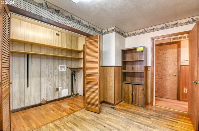 interior space with hardwood / wood-style floors, a textured ceiling, and wood walls