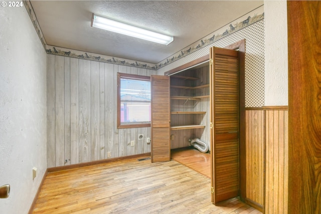 interior space with wood walls, wood-type flooring, and a textured ceiling