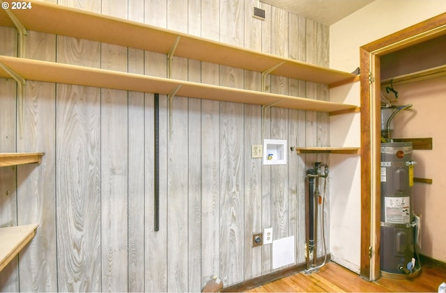 laundry room with electric dryer hookup, water heater, light hardwood / wood-style floors, and washer hookup