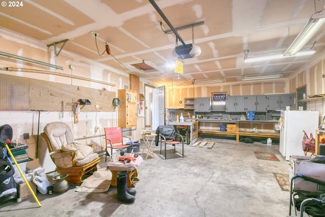 garage with a workshop area, white fridge, and a garage door opener