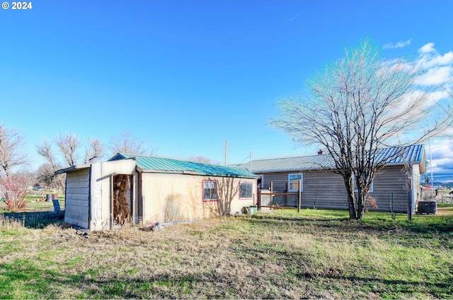 back of property featuring central air condition unit and a lawn