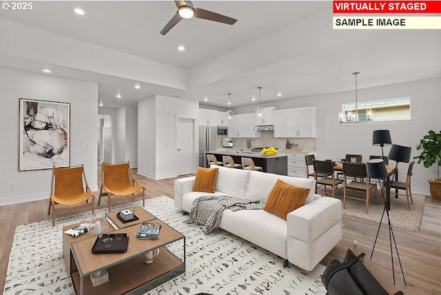 living room featuring sink, ceiling fan with notable chandelier, and light wood-type flooring