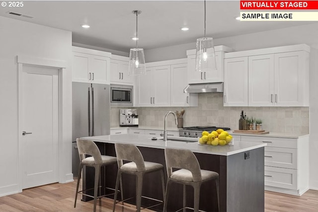 kitchen with stainless steel appliances, sink, a center island with sink, and white cabinets