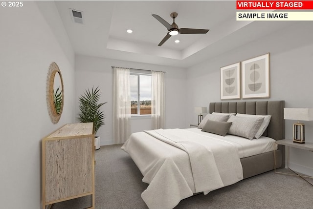 bedroom with ceiling fan, a raised ceiling, and dark carpet