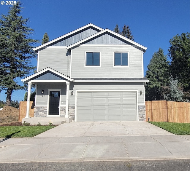 view of front of property with stone siding, fence, driveway, and an attached garage