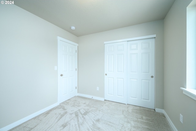 unfurnished bedroom with a closet and light carpet