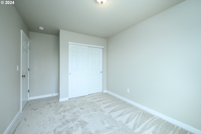 unfurnished bedroom featuring light carpet and a closet