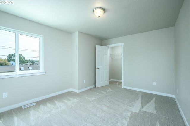 unfurnished bedroom with light colored carpet and a closet