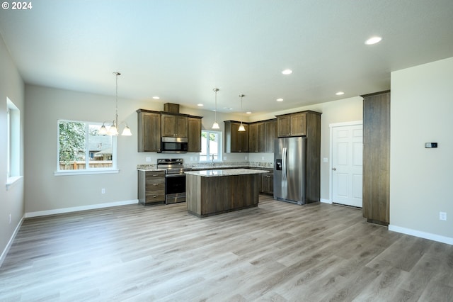 kitchen featuring a center island, light hardwood / wood-style floors, appliances with stainless steel finishes, hanging light fixtures, and dark brown cabinets