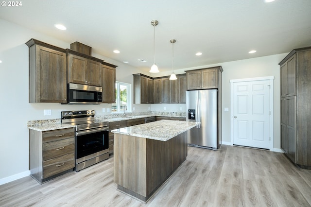 kitchen with a center island, light hardwood / wood-style floors, appliances with stainless steel finishes, hanging light fixtures, and sink