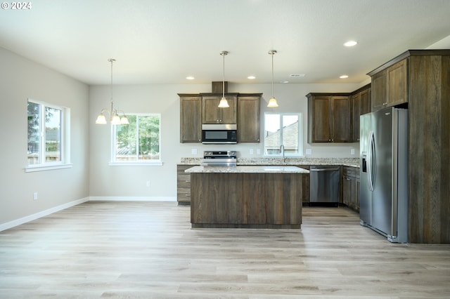 kitchen with hanging light fixtures, a center island, stainless steel appliances, and a healthy amount of sunlight