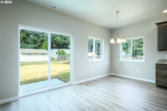 unfurnished dining area featuring a notable chandelier and light hardwood / wood-style floors