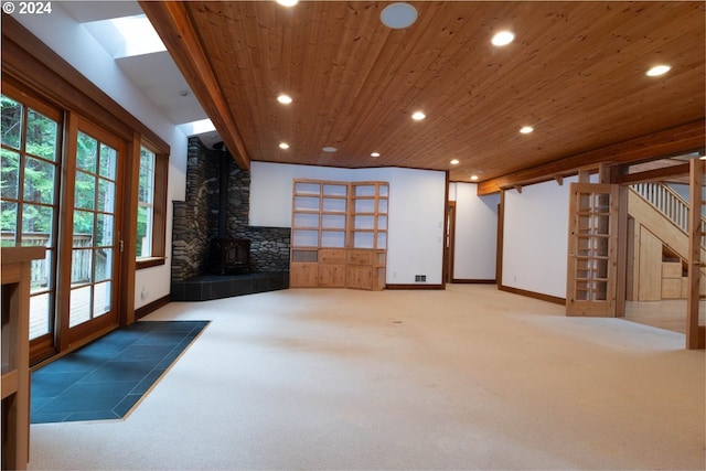 living room with a wood stove, carpet floors, and wooden ceiling