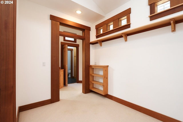 hall with lofted ceiling and light carpet