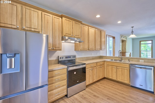 kitchen featuring hanging light fixtures, light wood-type flooring, appliances with stainless steel finishes, sink, and light brown cabinets