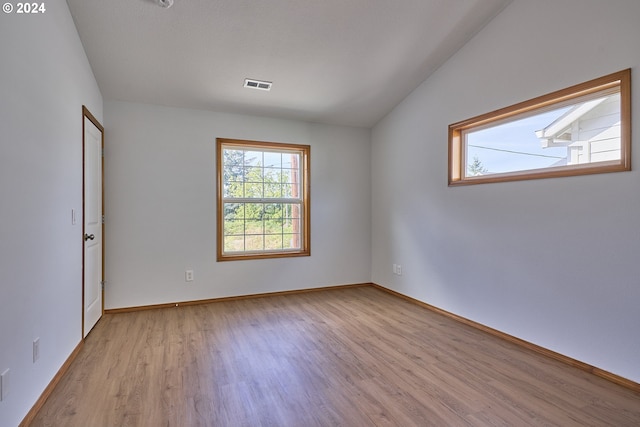 spare room with lofted ceiling and light hardwood / wood-style floors