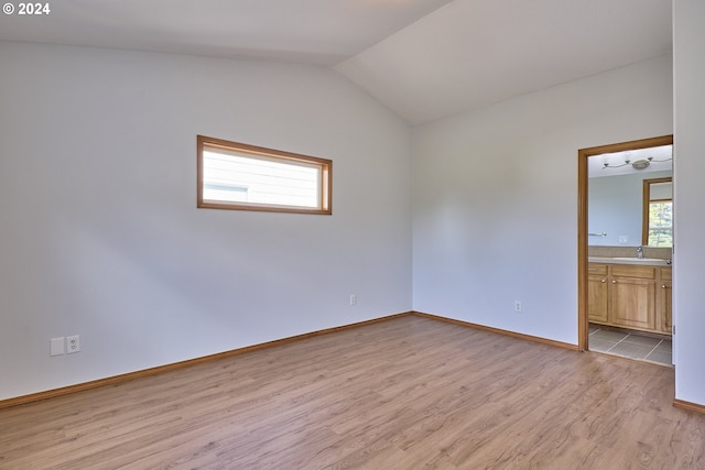 spare room featuring vaulted ceiling, sink, and light wood-type flooring