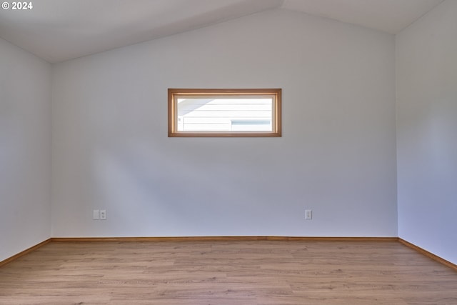 empty room featuring lofted ceiling and light hardwood / wood-style flooring