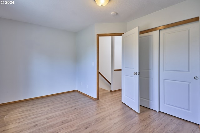 unfurnished bedroom featuring light wood-type flooring, a textured ceiling, and a closet