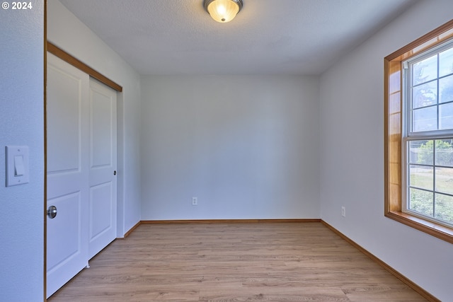 unfurnished bedroom featuring a textured ceiling, light hardwood / wood-style flooring, and a closet