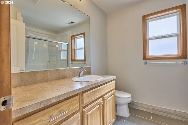 bathroom with vanity, toilet, and a shower with door