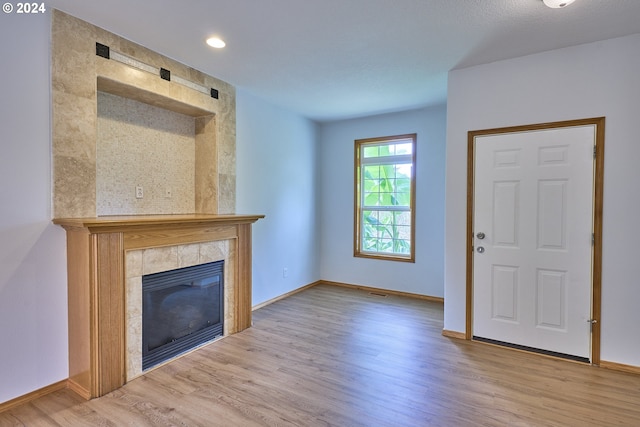 unfurnished living room featuring a fireplace and light hardwood / wood-style floors