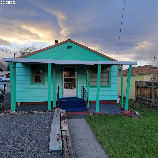 bungalow-style home featuring covered porch and a lawn