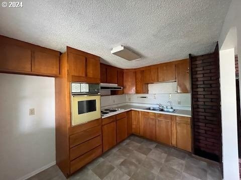 kitchen featuring white appliances, sink, and a textured ceiling